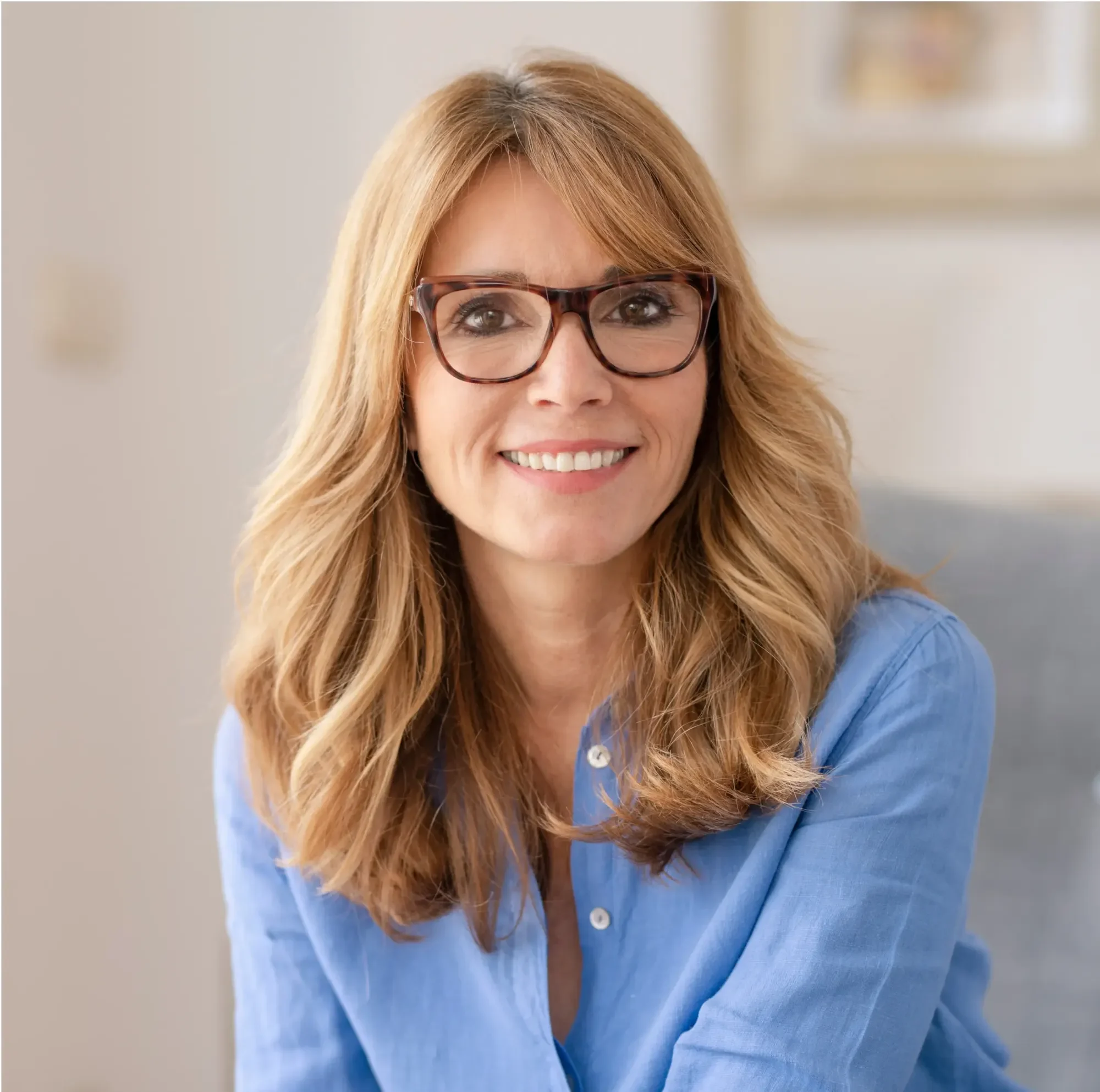 A smiling woman in her forties wearing glasses, seated at home | Complete Smiles-Cottonwood Heights-Mountain View-Redwood-Utah